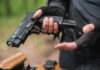 New Jersey AG’s GLARING Gun Grab Exposed! Person holding a handgun with tactical gloves outdoors