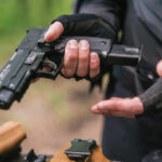 Person holding a handgun with tactical gloves outdoors