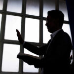 FEC Complaint ROCKS Megachurch Pastor’s Senate Launch Silhouette of a person holding a book and raising a hand