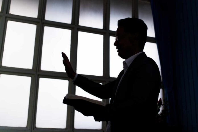 Silhouette of a person holding a book and raising a hand