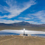 Aerial view of a solar power plant with a central tower and surrounding mirrors in a desert