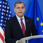 No Funding Plan? Becerra’s Risky Healthcare Promise Government official speaking at a podium with flags in the background
