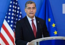 No Funding Plan? Becerra’s Risky Healthcare Promise Government official speaking at a podium with flags in the background