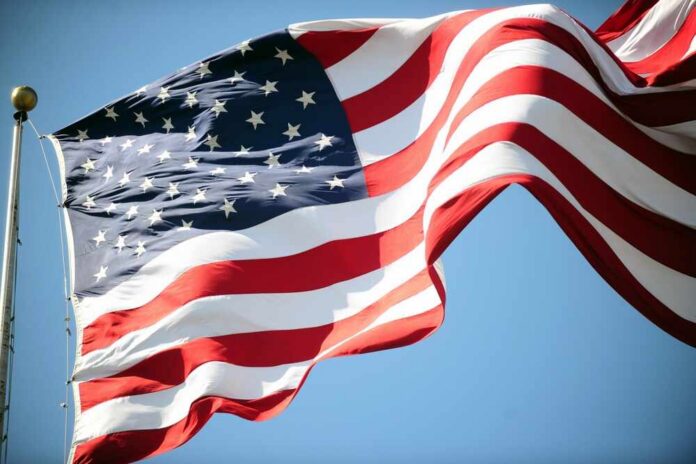 shutterstock_2598353049.jpg Waving American flag against a clear blue sky