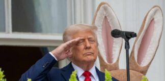 A man in a suit saluting in front of a floral display during an Easter event
