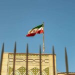 Iran Targets American Journalist: Alarming Plot Unveiled Iranian flag waving above a government building against a blue sky
