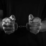 Hands holding handcuffs in a black and white image