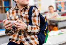 Your Son May Be Dating an AI Right Now — Schools Are Sounding the Alarm Child with smartphone and backpack sitting in classroom