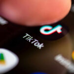 Finger tapping TikTok app on a smartphone screen