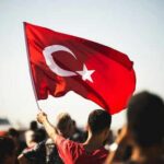 Turkish Police Storm Opposition HQ—Gas Deployed! Person waving Turkish flag in a crowd