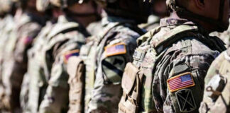 Soldiers in camouflage with American flag patches standing