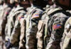 Marine Hero’s Sacrifice Exploited for Anti-War Agenda Soldiers in camouflage with American flag patches standing