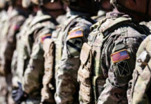 Marine Hero’s Sacrifice Exploited for Anti-War Agenda Soldiers in camouflage with American flag patches standing