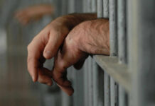 Judge Drops Hammer On Taliban Commander – 42 Years Hands resting on jail cell bars.