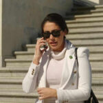 Person in white jacket talking on phone, wearing sunglasses.