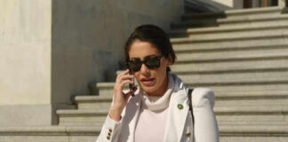 Person in white jacket talking on phone, wearing sunglasses.