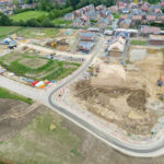 Aerial view of a housing construction site beside a residential neighborhood