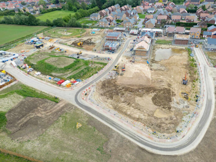 Aerial view of a housing construction site beside a residential neighborhood