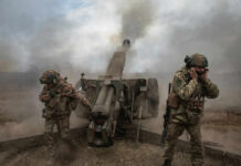 Trump-Era Push Collides With Pentagon Habit Soldiers fire a field howitzer as smoke and dust rise around them