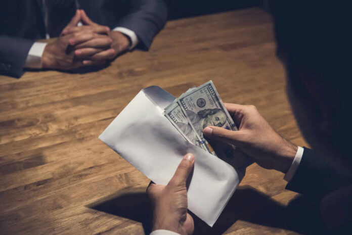 Hands placing cash into an envelope at a wooden table