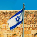 Israeli flag waving in front of an ancient stone wall