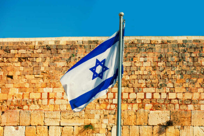 Israeli flag waving in front of an ancient stone wall
