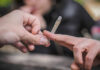 Hands passing a lit joint between people