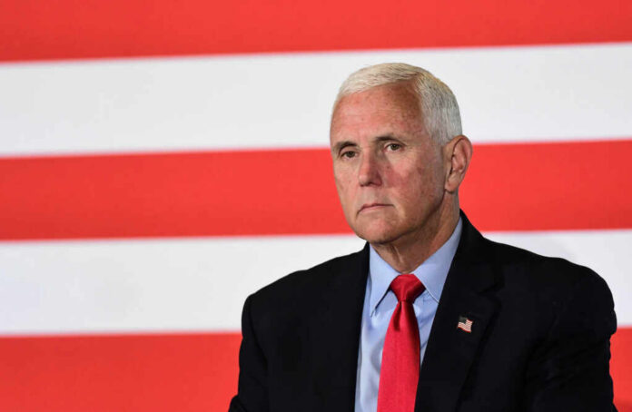 mike-pence-speaks2358120659jpg man in suit with red tie in front of red and white stripes