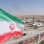 Iranian flag waving in front of an oil processing facility