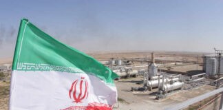 Iranian flag waving in front of an oil processing facility