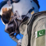 Close-up of a military pilot wearing a helmet and a uniform with a Pakistan flag patch