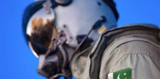 Close-up of a military pilot wearing a helmet and a uniform with a Pakistan flag patch