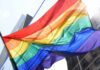 Utility Deals Now Identity-Tagged A vibrant rainbow flag waving against a city backdrop