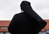 Jail Threat For Nuns Sparks Federal Clash A nun in black attire standing outdoors with a cloudy sky in the background
