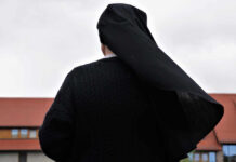 Jail Threat For Nuns Sparks Federal Clash A nun in black attire standing outdoors with a cloudy sky in the background