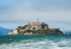 Alligator Alcatraz Blinked at First Big Gust View of Alcatraz Island with buildings and lighthouse surrounded by water