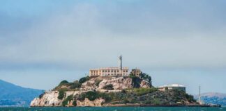 View of Alcatraz Island with buildings and lighthouse surrounded by water