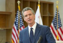 Newsom’s Rush Raises Red Flags A government official speaking at a podium with American flags in the background