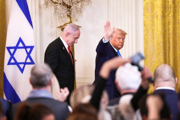 Two suited men at a formal event with an Israeli flag and audience