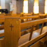 Wooden church pew with carved cross in a sunlit sanctuary