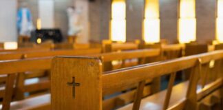 Wooden church pew with carved cross in a sunlit sanctuary