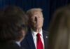 Trump Tsunami Flattens GOP Holdouts A serious-looking man in a suit with a red tie, surrounded by blurred figures