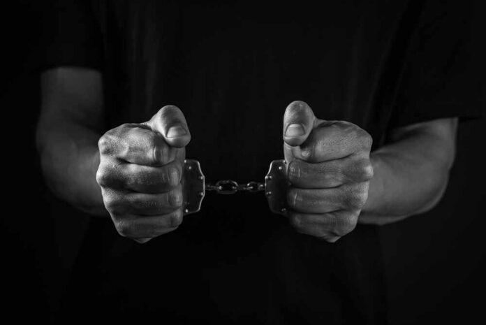 Handcuffed,Man,In,Darkness,,Closeup.,Captured,Criminal.,Black,And,White Hands holding handcuffs in a black and white image