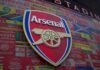Arsenal Parade Mayhem: Flares Spark Hotel Inferno A crowded street with individuals sitting behind barriers and bags, highlighting urban homelessness