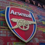 Arsenal Parade Mayhem: Flares Spark Hotel Inferno A crowded street with individuals sitting behind barriers and bags, highlighting urban homelessness