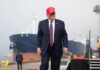 G7 Laughs—Then Things Get Tense A man in a suit wearing a red cap stands near a ship at a harbor