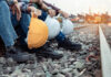 Railway workers sitting on track ballast holding hard hats
