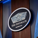 War Powers Meltdown: Who’s Really In Charge? The Pentagon emblem between two flags.