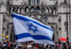 Israeli Power Play: U.S. Takes The Hits Israeli flag at a crowded outdoor event.