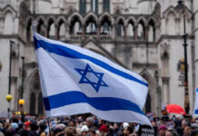 Israeli Power Play: U.S. Takes The Hits Israeli flag at a crowded outdoor event.